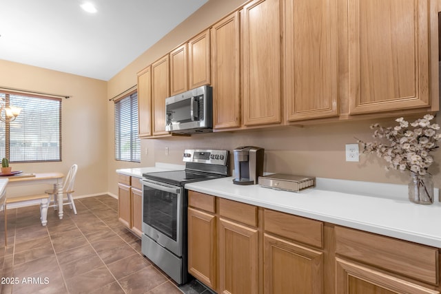 kitchen featuring light brown cabinetry, stainless steel appliances, tile patterned flooring, baseboards, and light countertops