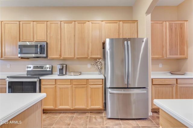 kitchen with arched walkways, light brown cabinets, stainless steel appliances, and light countertops