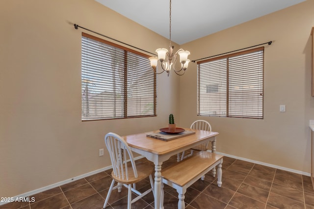 dining room with baseboards, plenty of natural light, dark tile patterned flooring, and a chandelier