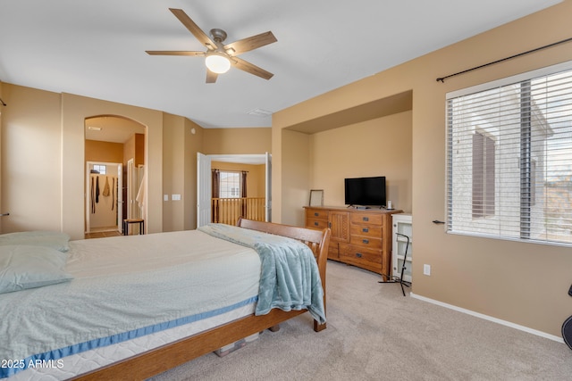 bedroom featuring arched walkways, ceiling fan, light carpet, and baseboards