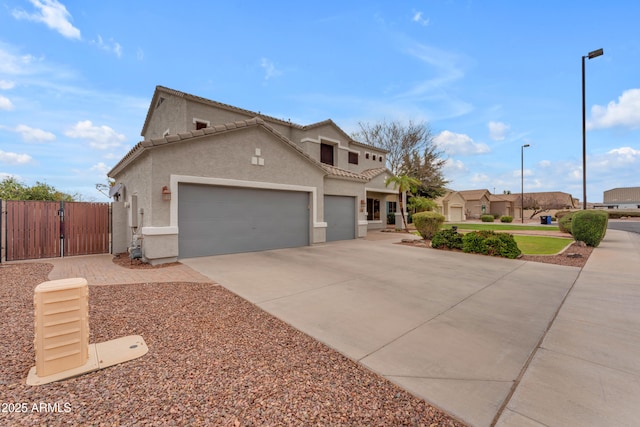 view of front of house featuring a gate, driveway, an attached garage, stucco siding, and a tile roof