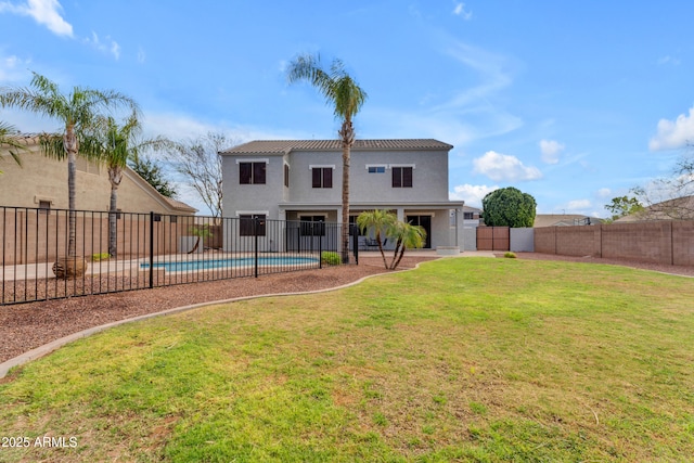 rear view of house featuring stucco siding, a lawn, a tile roof, a fenced backyard, and a fenced in pool