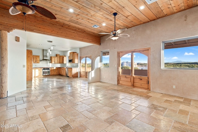 unfurnished living room featuring beamed ceiling, ceiling fan, and wood ceiling