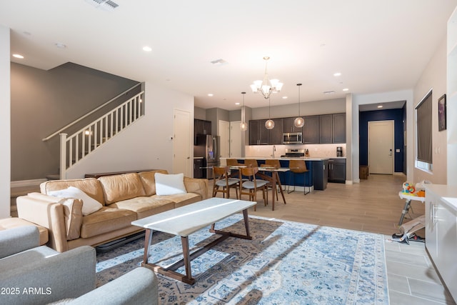 living room with light hardwood / wood-style floors, sink, and an inviting chandelier