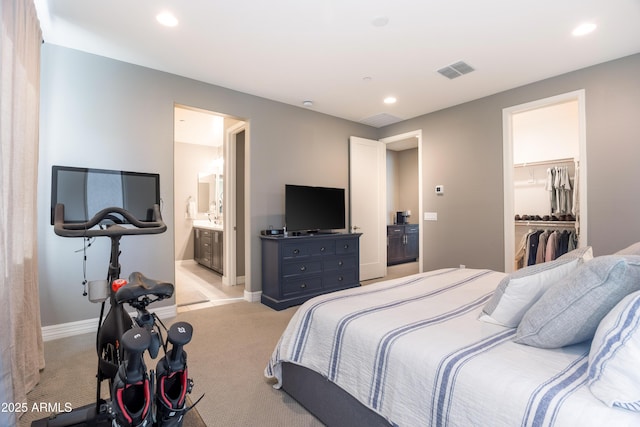 carpeted bedroom with a walk in closet, ensuite bathroom, and a closet