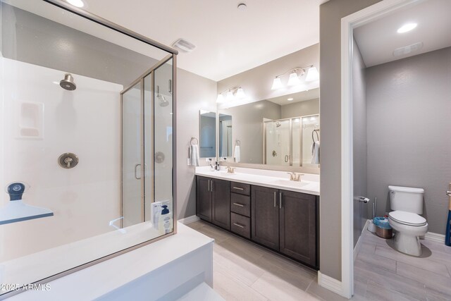 bathroom with vanity, a shower with shower door, and toilet