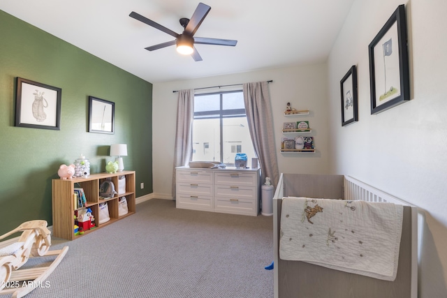 carpeted bedroom featuring ceiling fan and a nursery area