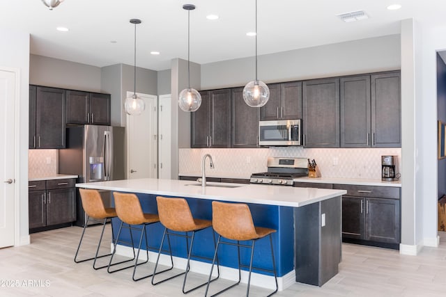 kitchen featuring dark brown cabinets, a kitchen island with sink, and appliances with stainless steel finishes