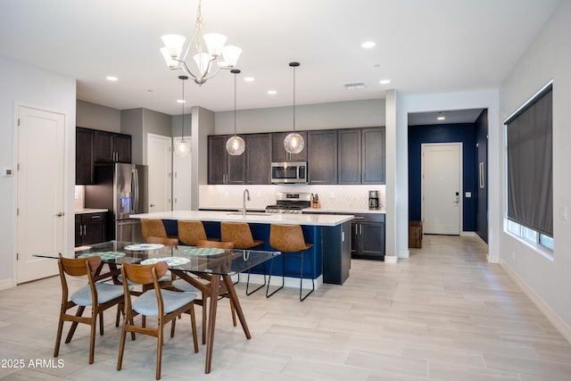 kitchen featuring pendant lighting, dark brown cabinets, an island with sink, and stainless steel appliances