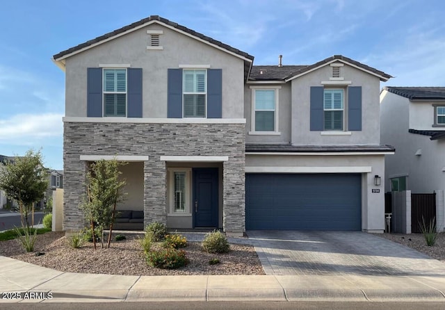 traditional-style house with stucco siding, stone siding, an attached garage, and driveway