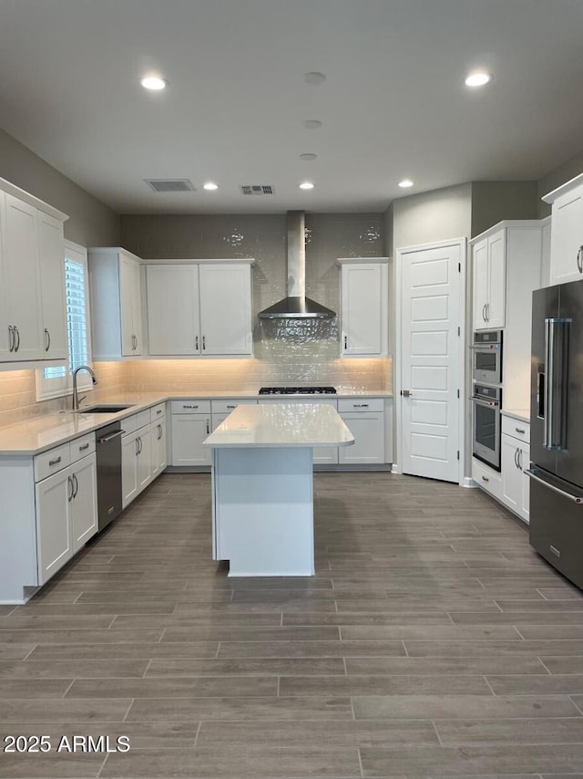 kitchen with a sink, decorative backsplash, wall chimney range hood, and stainless steel appliances