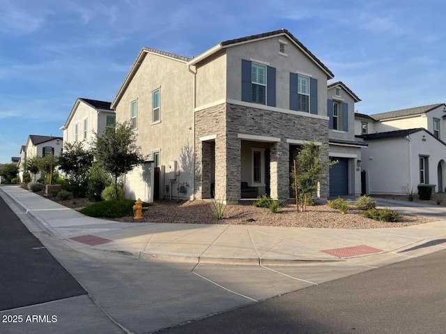 view of front of home with concrete driveway, an attached garage, stone siding, and stucco siding