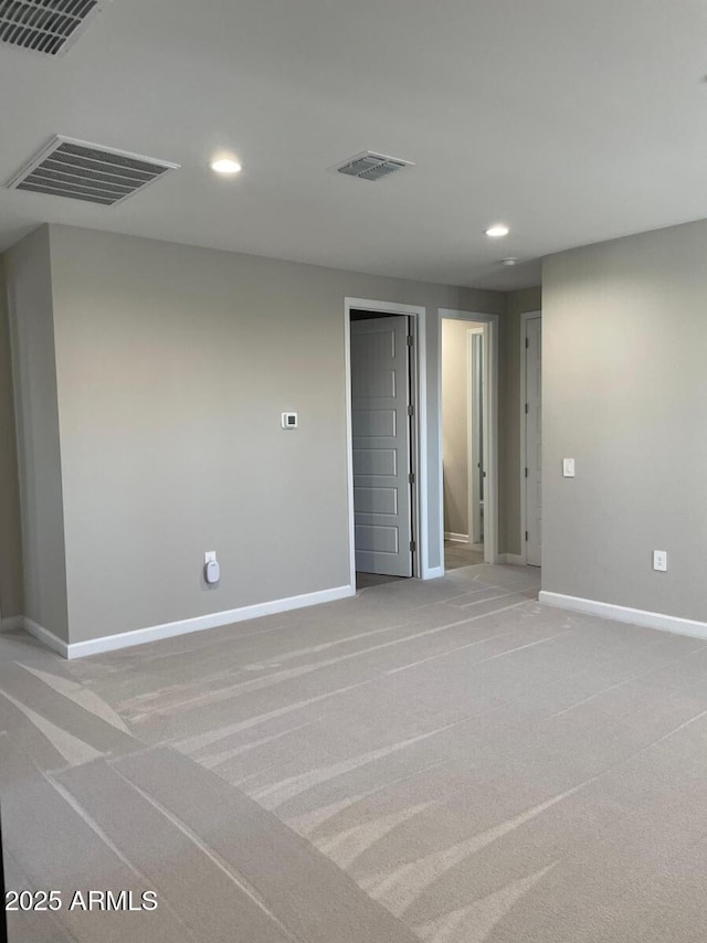 empty room with recessed lighting, visible vents, baseboards, and light carpet