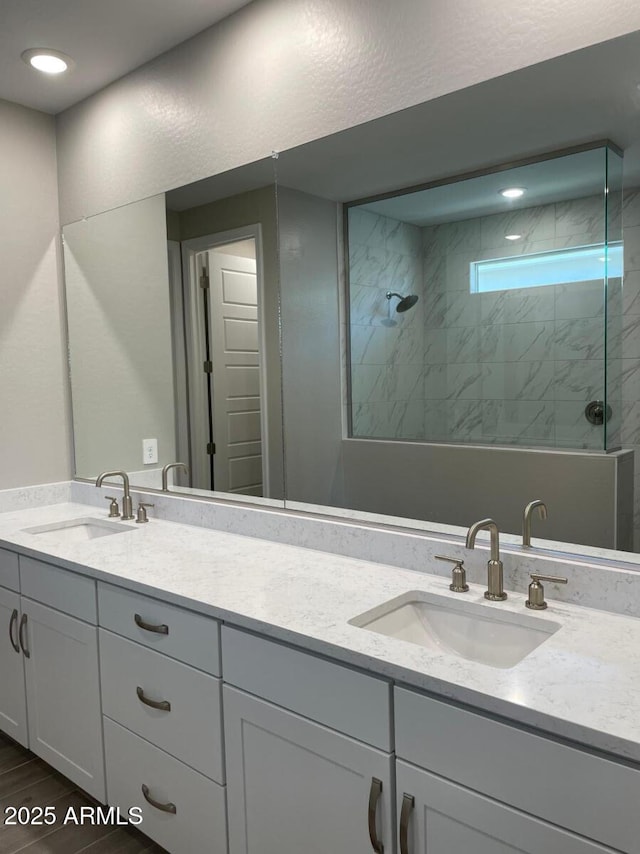 full bathroom with a tile shower, wood finished floors, and a sink