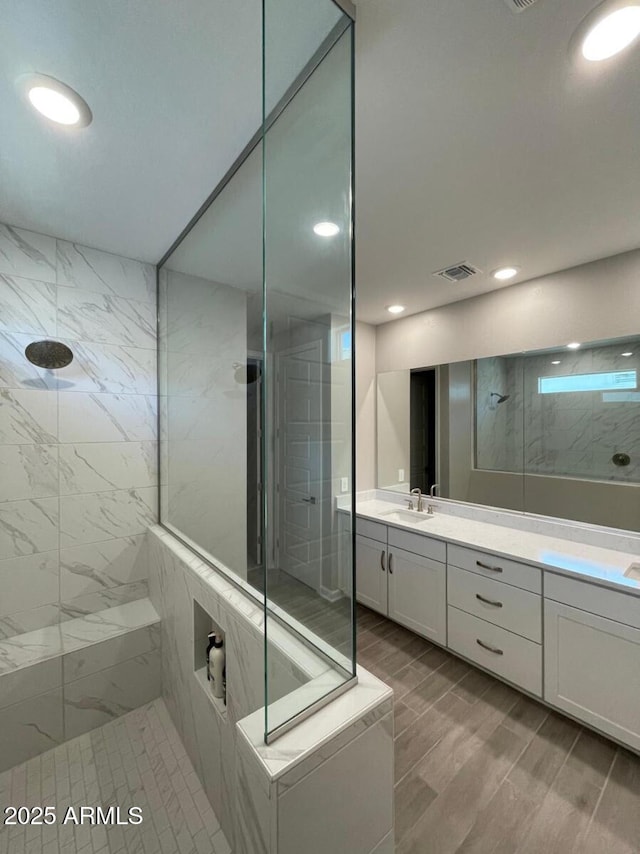 bathroom with visible vents, a walk in shower, vanity, and wood tiled floor