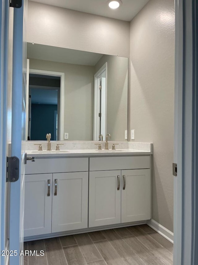 bathroom featuring double vanity, wood finish floors, and a sink