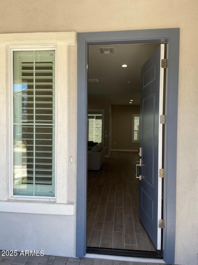 view of exterior entry with visible vents and stucco siding