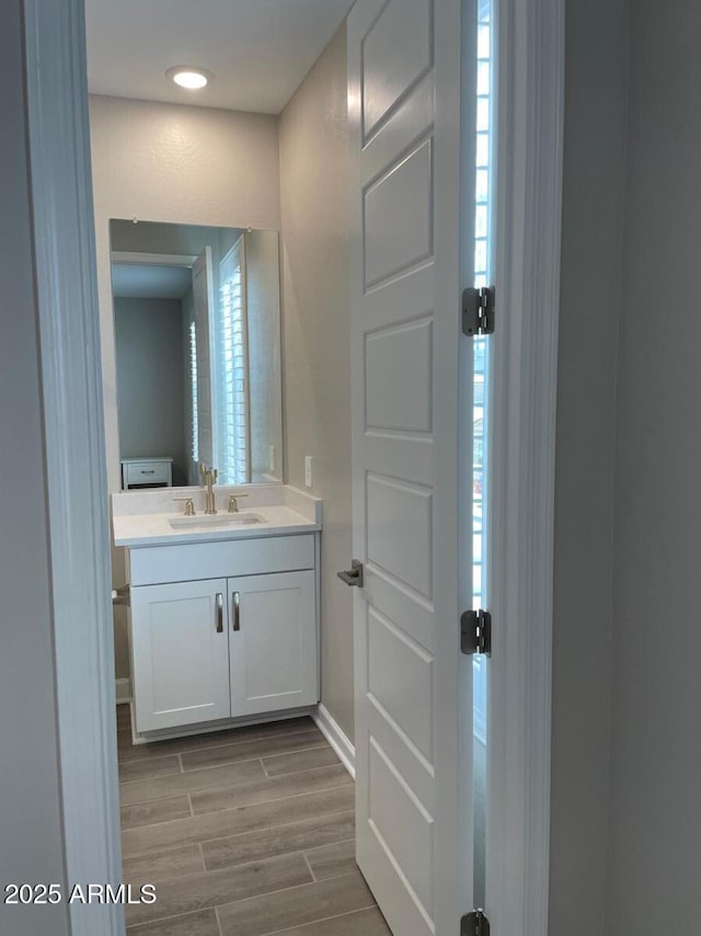 bathroom with wood finish floors, baseboards, plenty of natural light, and vanity