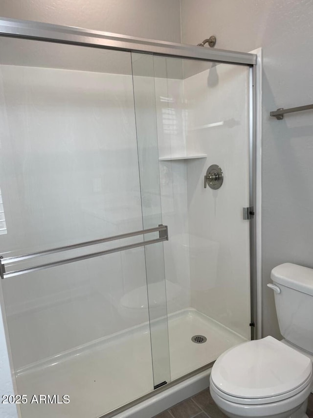 full bathroom featuring toilet and a stall shower