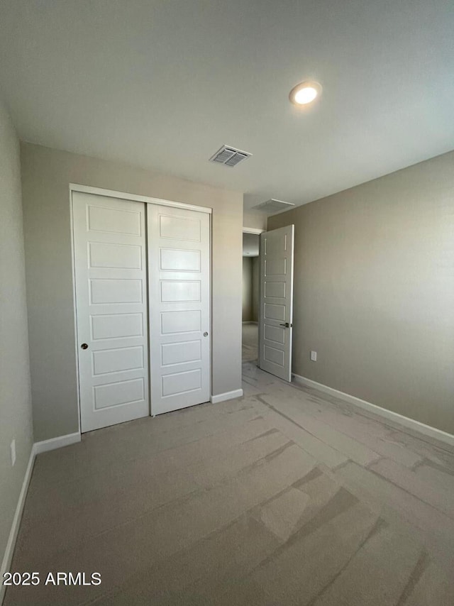 unfurnished bedroom featuring baseboards, visible vents, a closet, and carpet floors