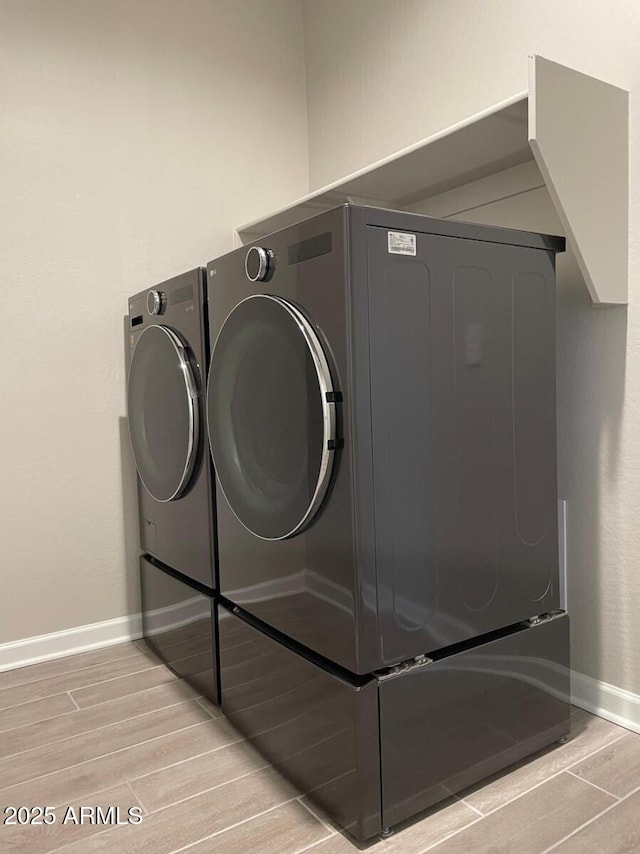 clothes washing area with laundry area, baseboards, independent washer and dryer, and wood tiled floor