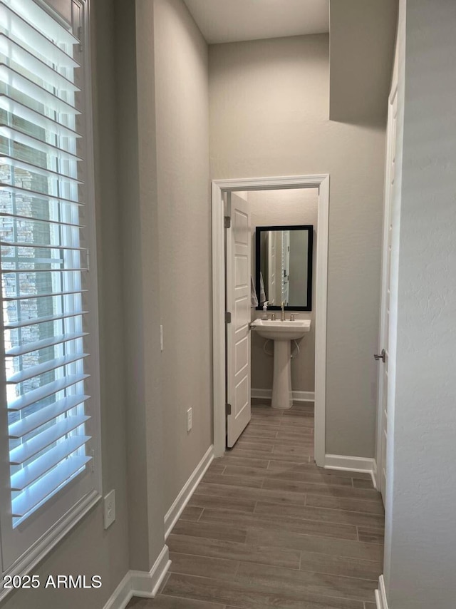 corridor featuring wood finish floors and baseboards