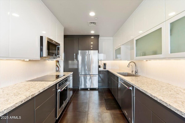 kitchen with a sink, stainless steel appliances, white cabinets, glass insert cabinets, and modern cabinets