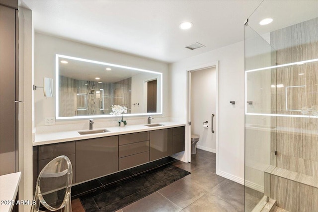 bathroom with a sink, toilet, double vanity, and a tile shower