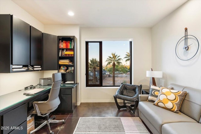 office with built in study area, baseboards, and dark tile patterned flooring