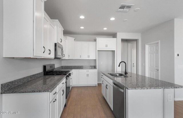 kitchen featuring white cabinetry, stainless steel appliances, sink, and dark stone countertops