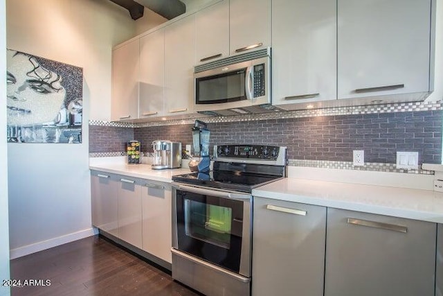 kitchen with gray cabinetry, backsplash, appliances with stainless steel finishes, and dark hardwood / wood-style flooring