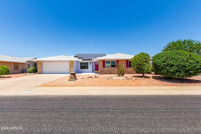 single story home with solar panels and a garage