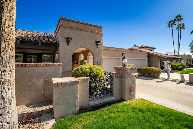 mediterranean / spanish house featuring a fenced front yard, stucco siding, an attached garage, driveway, and a tiled roof