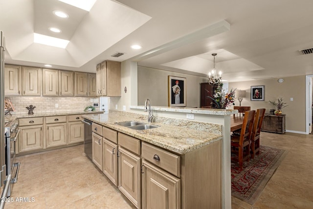 kitchen featuring a tray ceiling, cream cabinets, a sink, and stainless steel dishwasher