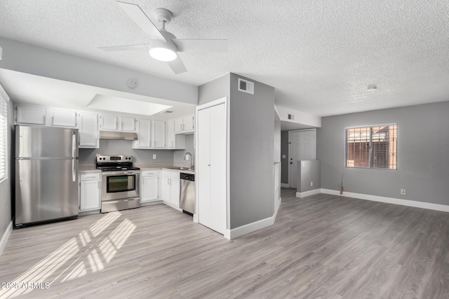 kitchen with appliances with stainless steel finishes, white cabinetry, sink, ceiling fan, and light hardwood / wood-style flooring