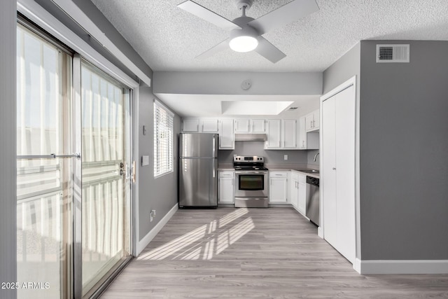 kitchen featuring white cabinets, stainless steel appliances, sink, ceiling fan, and light hardwood / wood-style flooring