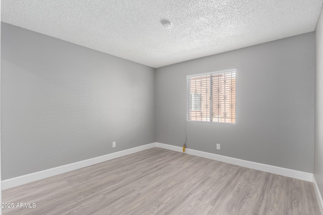 spare room with a textured ceiling and light hardwood / wood-style flooring