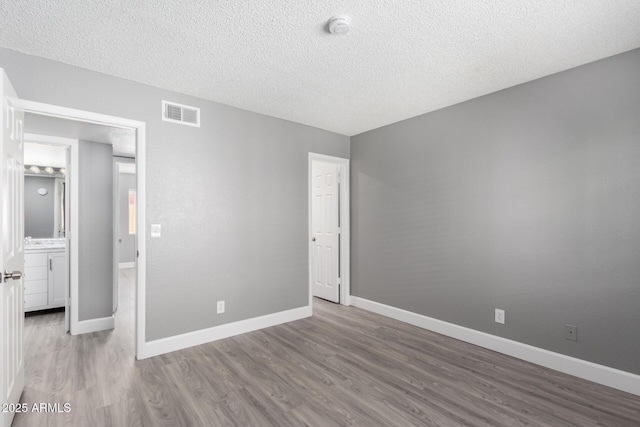 unfurnished bedroom with a textured ceiling and hardwood / wood-style flooring