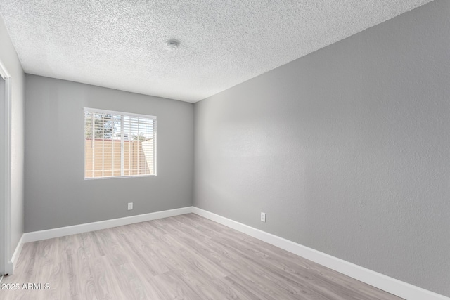 unfurnished room featuring a textured ceiling and light wood-type flooring