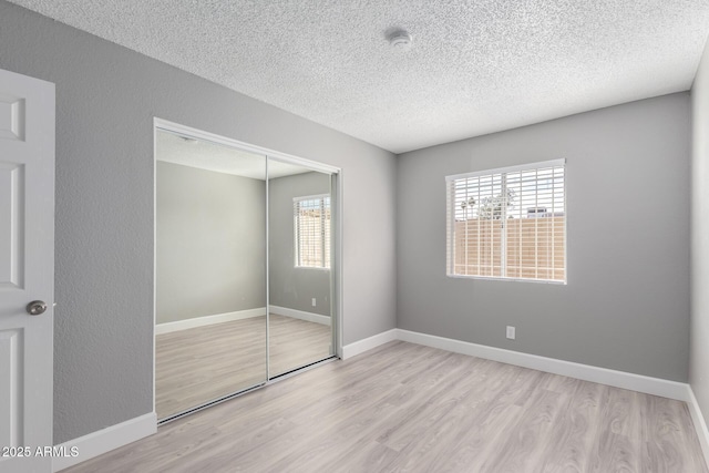 unfurnished bedroom with a closet, a textured ceiling, and light hardwood / wood-style floors