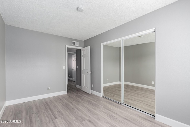 unfurnished bedroom featuring a textured ceiling, a closet, and light hardwood / wood-style floors