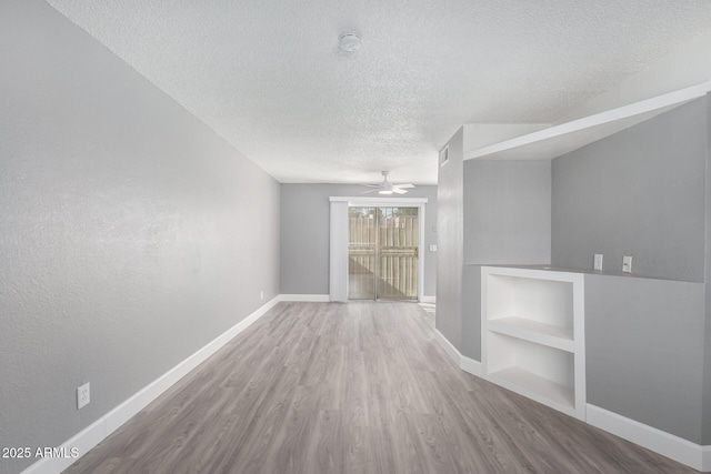 unfurnished room featuring hardwood / wood-style flooring, a textured ceiling, built in features, and ceiling fan