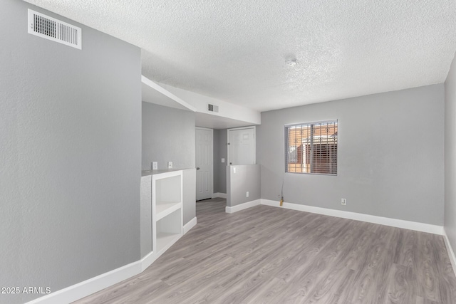 unfurnished room featuring a textured ceiling and light hardwood / wood-style floors