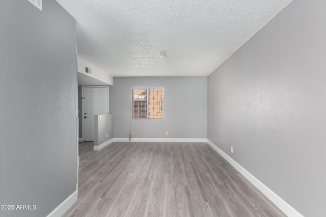 unfurnished room featuring a textured ceiling and light wood-type flooring