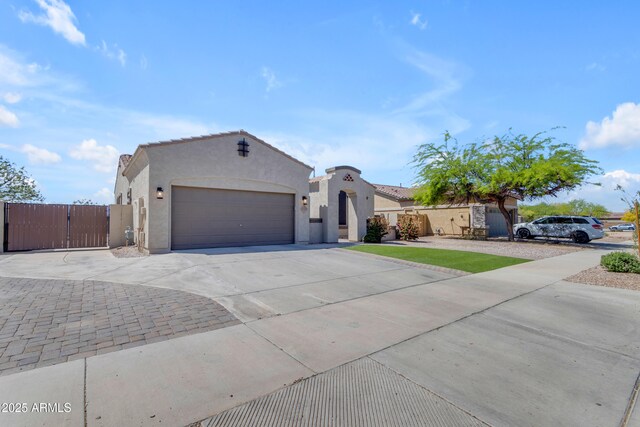 ranch-style house with a tiled roof, a garage, concrete driveway, stucco siding, and a gate