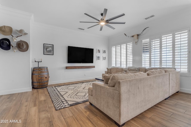 living area featuring light wood-type flooring, crown molding, a ceiling fan, and visible vents