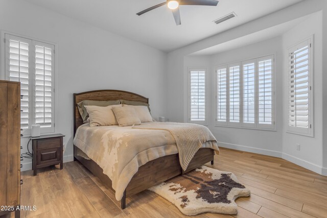 bedroom with ceiling fan, visible vents, baseboards, and wood finished floors