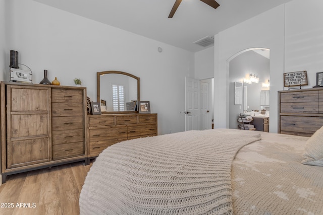 bedroom featuring arched walkways, ceiling fan, visible vents, and light wood-style floors