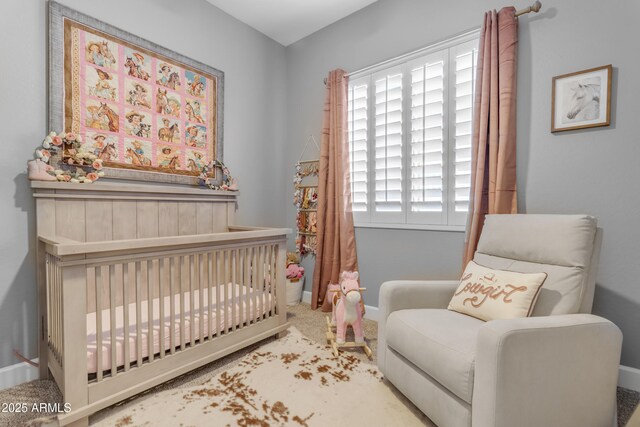 carpeted bedroom featuring baseboards and a nursery area