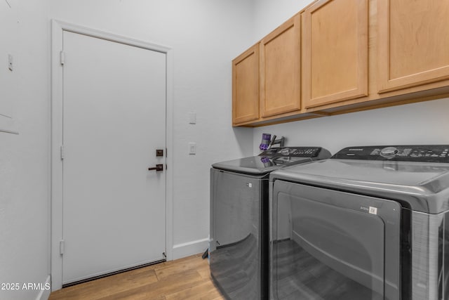 washroom featuring light wood-style flooring, independent washer and dryer, and cabinet space